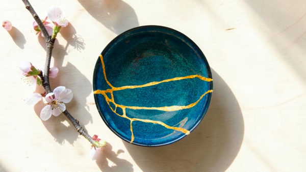 Kintsugi-repaired ceramic bowl with gold seams and cherry blossom branch
